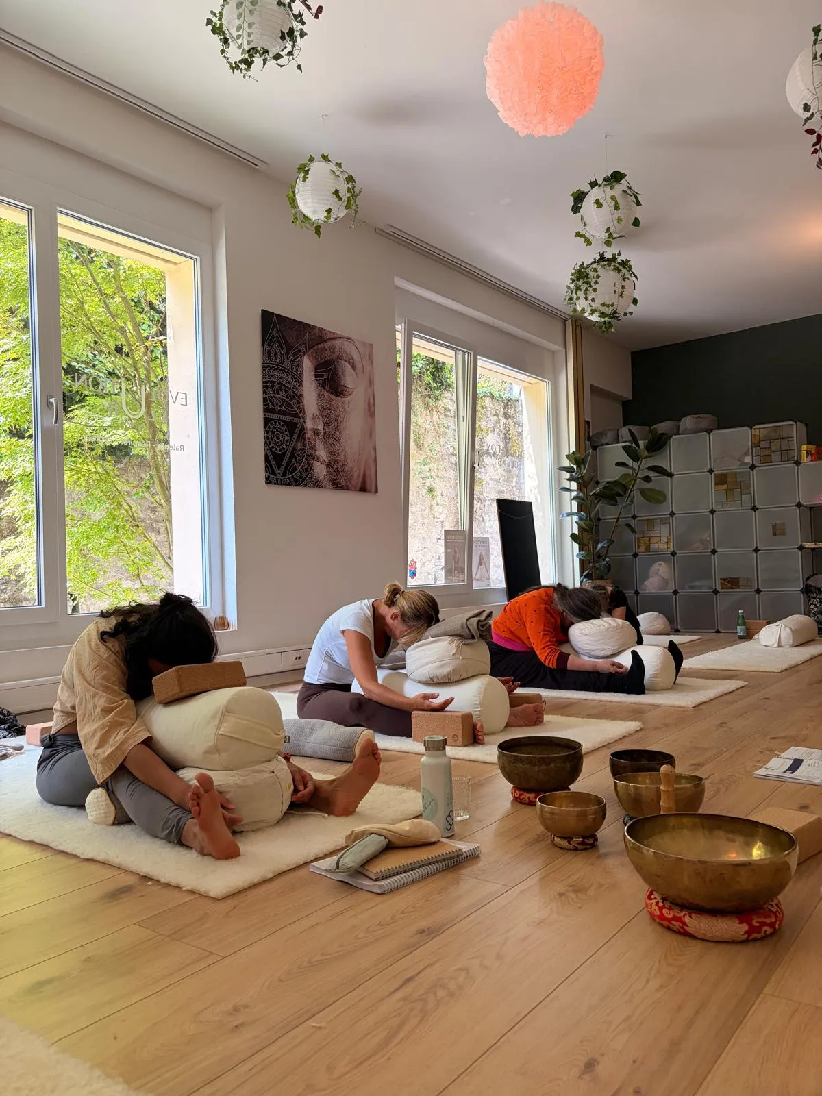 A small group practising a gentle seated pose over bolsters during a class